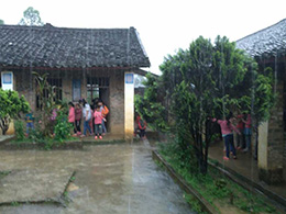 暴雨中，教室里出現漏水情況，學生們在屋檐下避雨